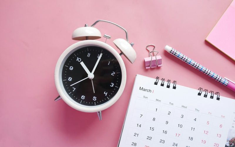 white and pink analog alarm clock